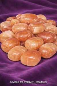 Buy crystals for creativity online including honey calcite stones on purple cloth