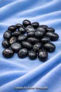 Buy crystals for focus online shown as black agni stones on sky blue cloth.