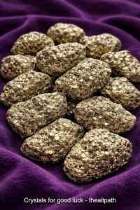 Shop crystals for good luck online with raw pyrite stones on dark purple cloth